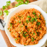 mexican red rice in white bowl sprinkled with cilantro
