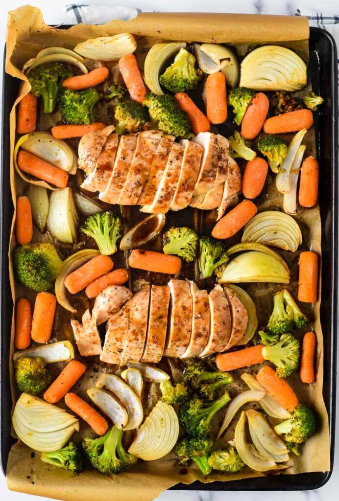 sheet pan with teriyaki chicken, onions, broccoli and carrots all drizzled in sauce