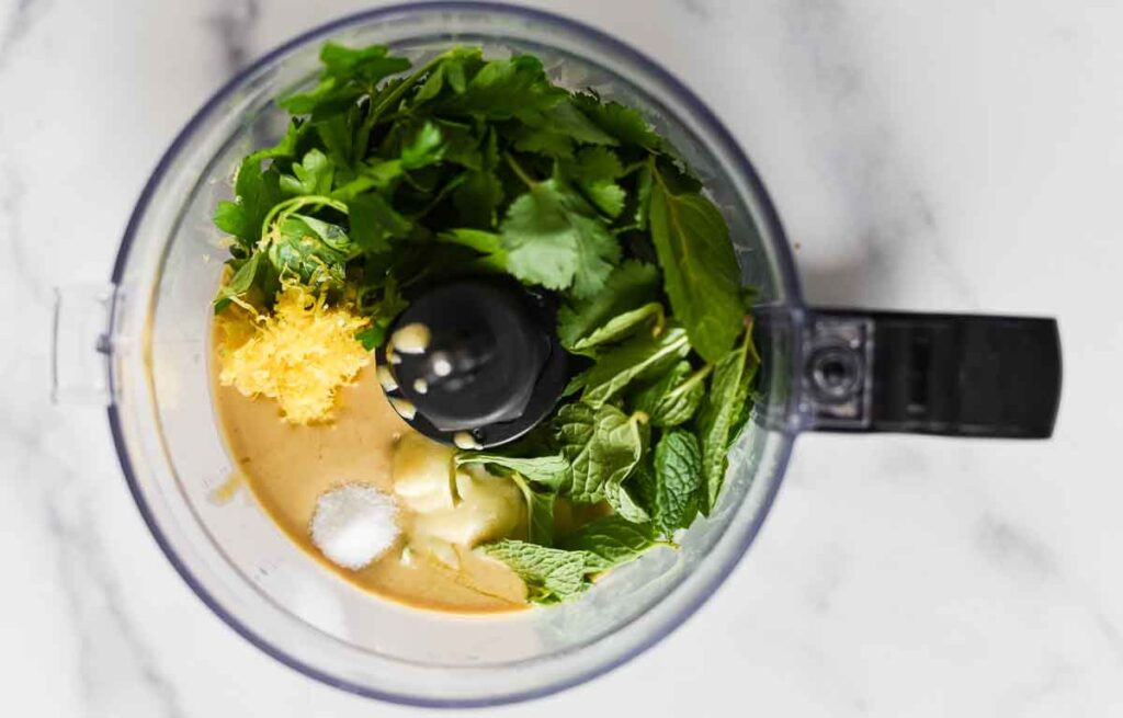 food processor bowl with ingredients for tahini sauce