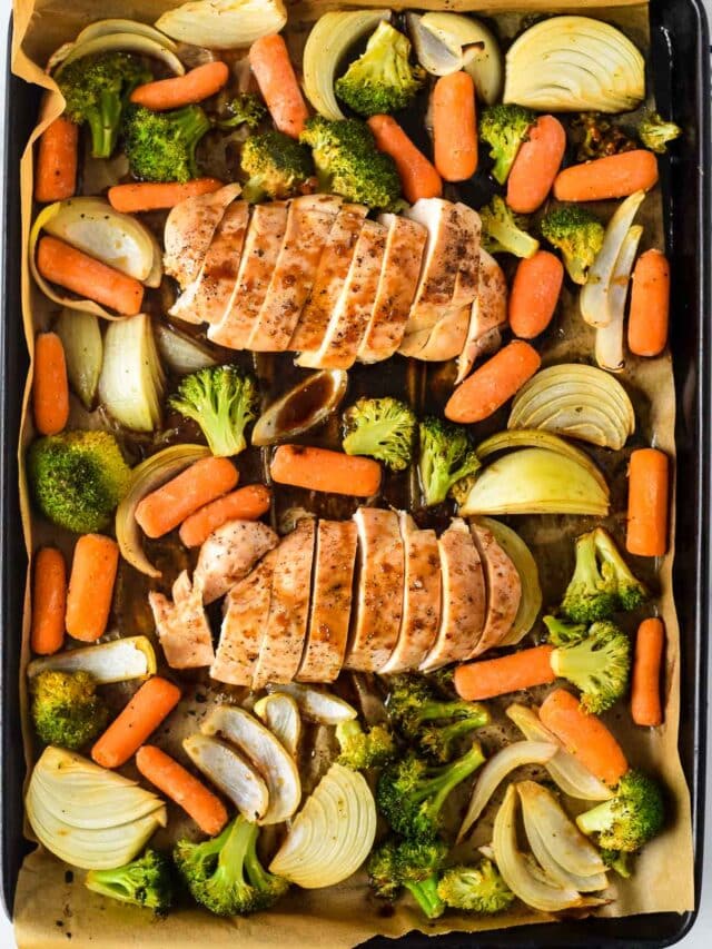 sheet pan with teriyaki chicken, onions, broccoli and carrots all drizzled in sauce