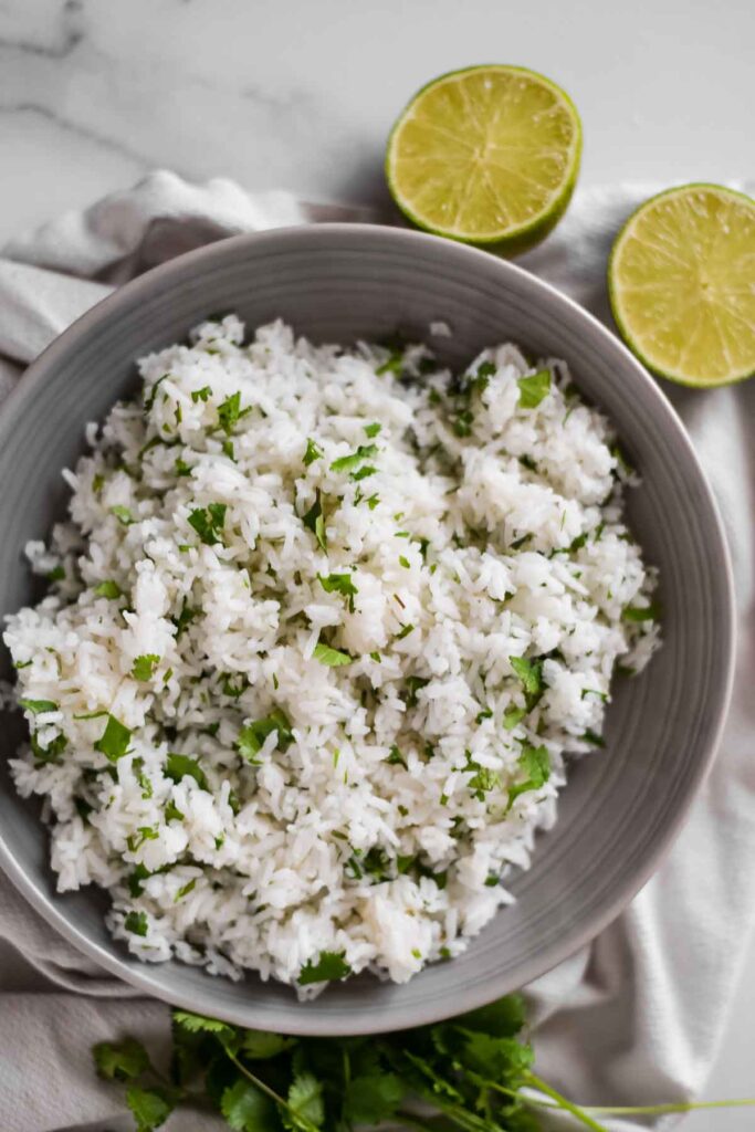 cilantro lime rice in grey serving bowl with lime wedges beside