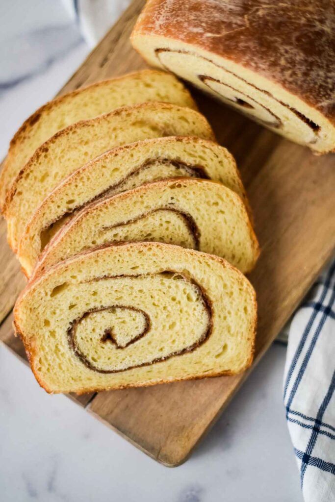 slices of cut cinnamon swirl bread layer out on cutting board to show off swirl pattern