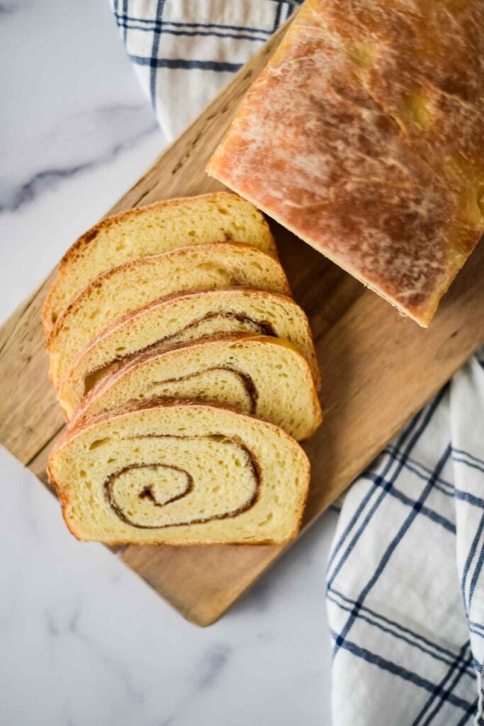sourdough cinnamon swirl loaf on cutting board with cut slices laying beside it