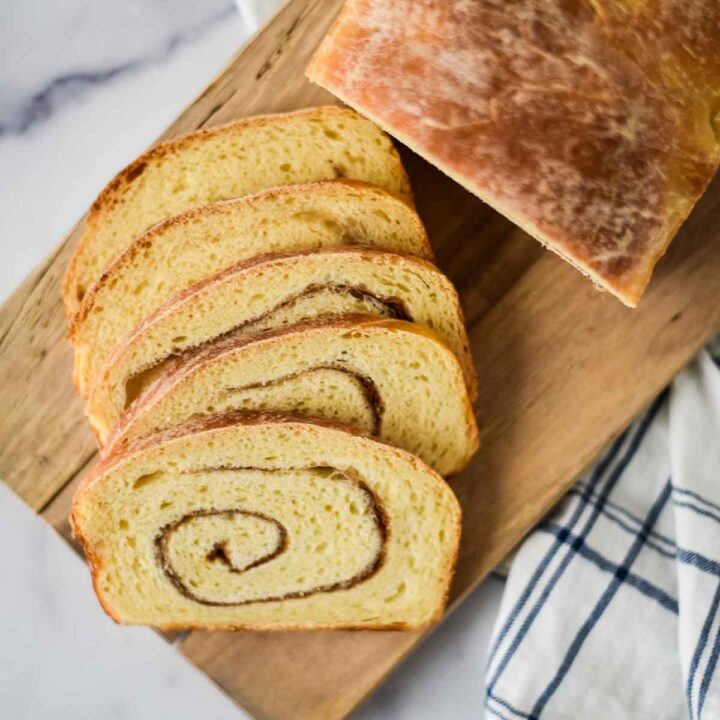 sourdough cinnamon swirl loaf on cutting board with cut slices laying beside it
