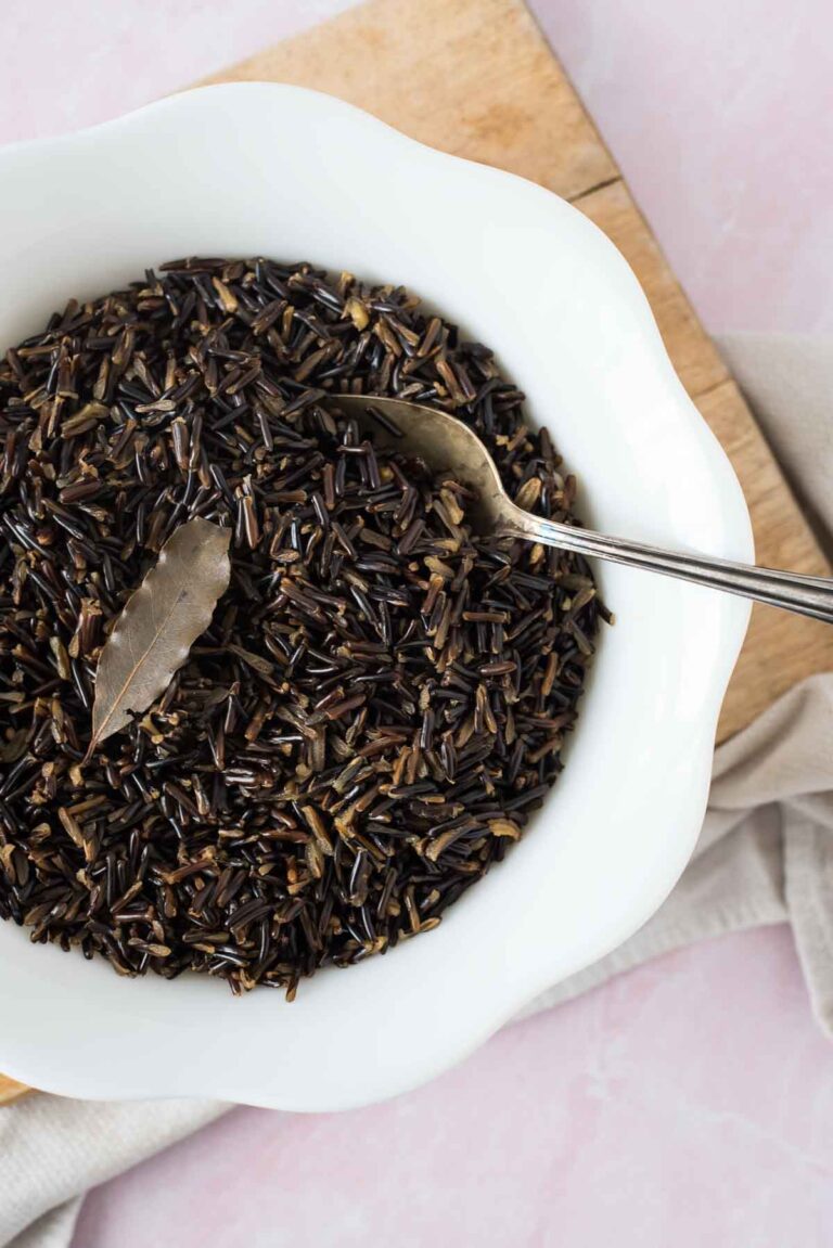 cooked wild rice in white bowl with serving spoon