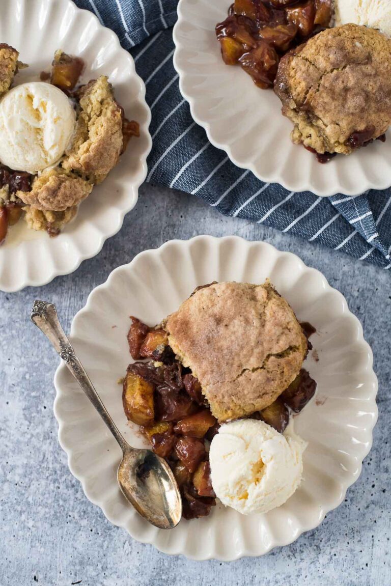 three white plates with peach cobbler made with sourdough biscuits