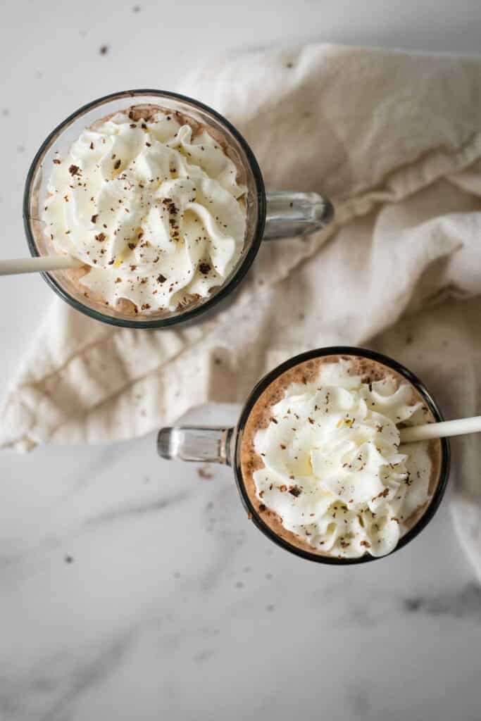 overhead view of two glass mugs with frozen hot chocolate topped with whipped cream