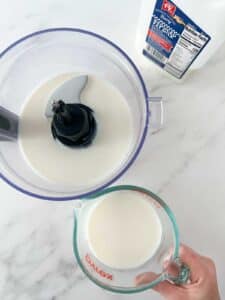 pouring milk from glass measuring jar into blender