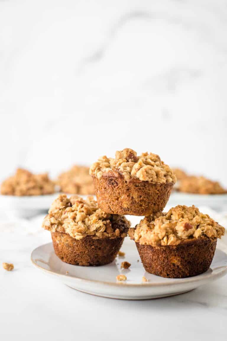 three muffins stacked on plate showing off crumb topping