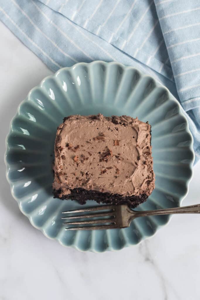 overhead view of piece of chocolate cake on blue plate with fork