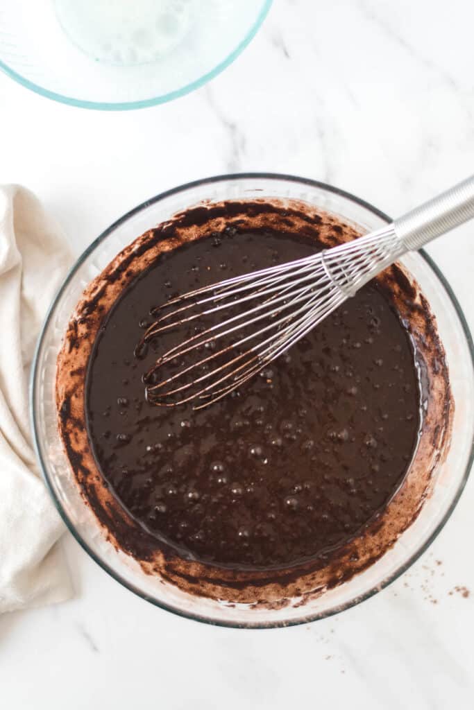 chocolate sponge cake batter in glass bowl with whisk