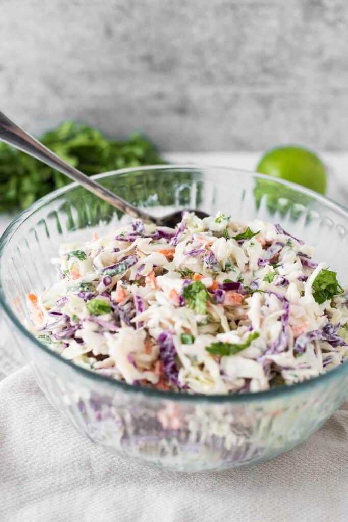 cilantro lime slaw in glass bowl with lime in background