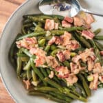 overhead closeup of german green beans with bacon in serving dish with spoon