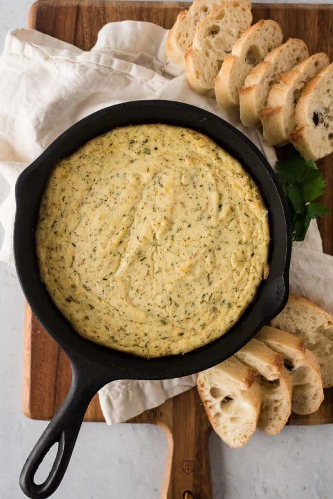 baked ricotta in cast iron skillet surrounded by slices of bread