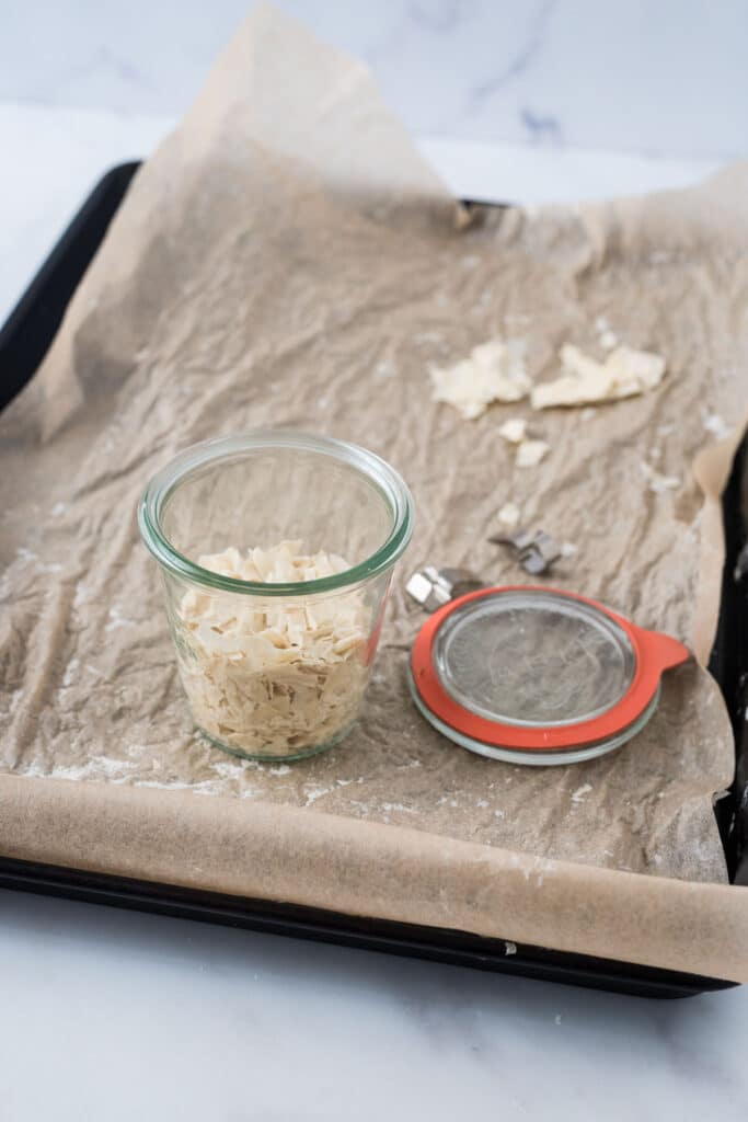 dried sourdough starter in glass container on sheet pan with more starter behind