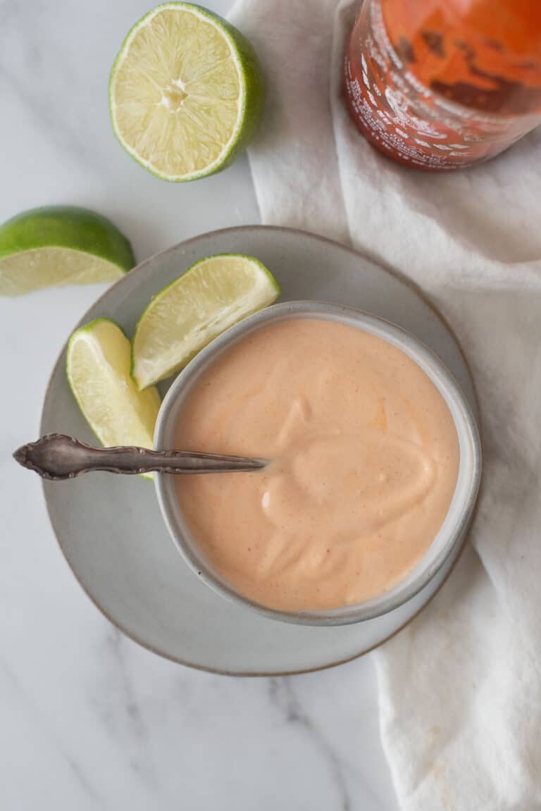 bowl of spicy mayo with spoon and lime wedges