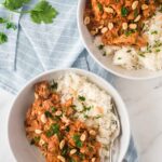 two bowls of peanut stew with chicken and rice topped with parsley