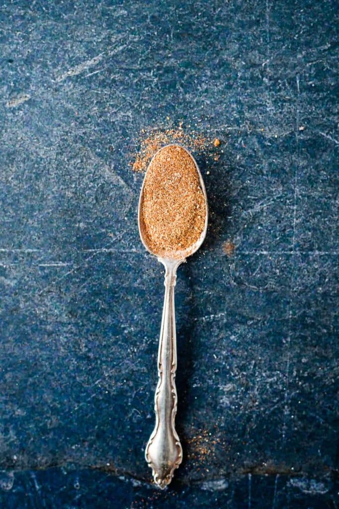 silver spoon on dark blue background filled with spice blend