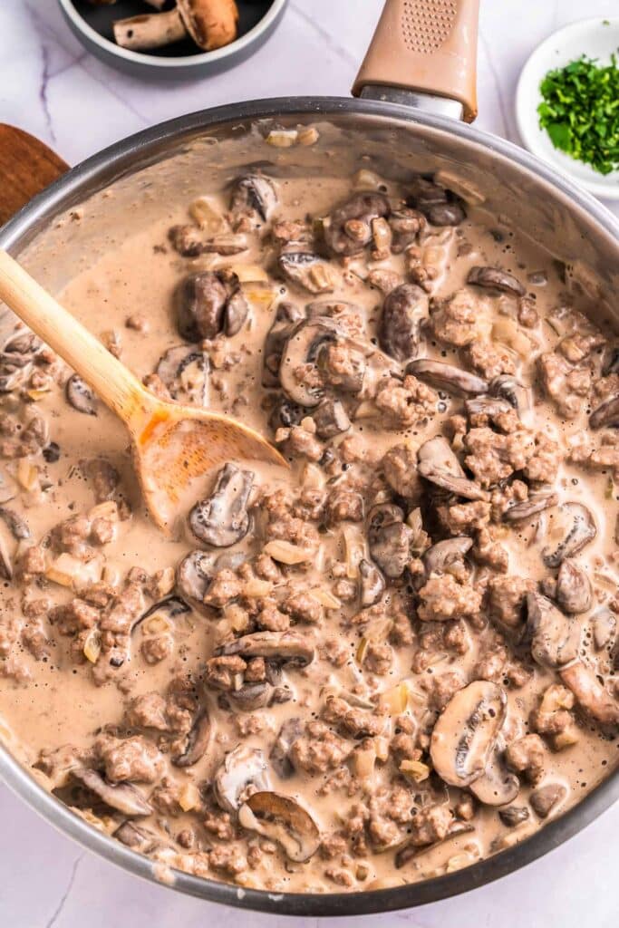 pan with ground beef and stroganoff sauce with wooden spoon