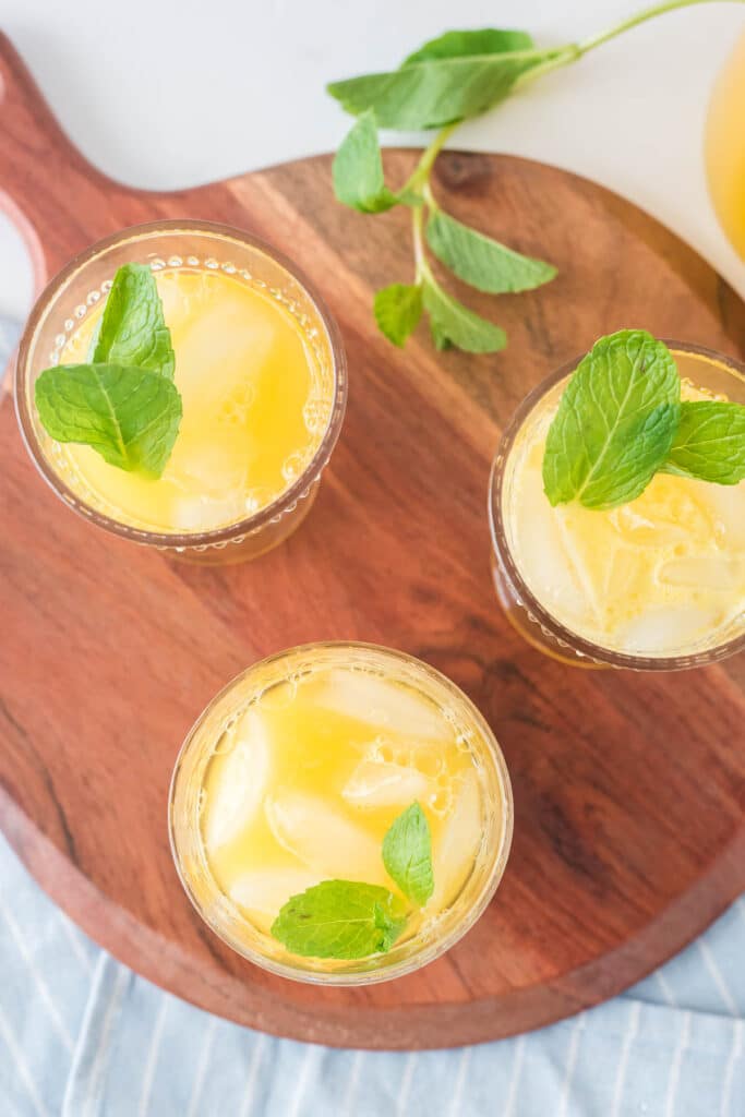 overhead shot of three glasses of mango lemonade with mint sprigs on top of each