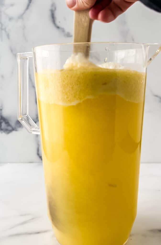 juice getting stirred in glass pitcher with wooden spoon