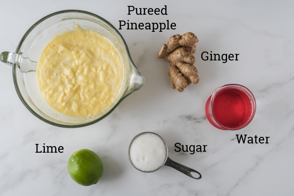 ingredients for pineapple ginger juice on marble with text overlay