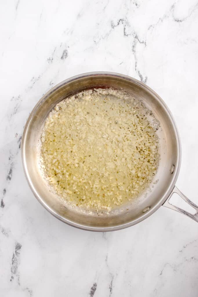 stainless steel pan with minced garlic and melted butter