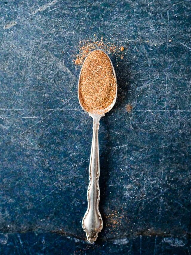 silver spoon on dark blue background filled with spice blend