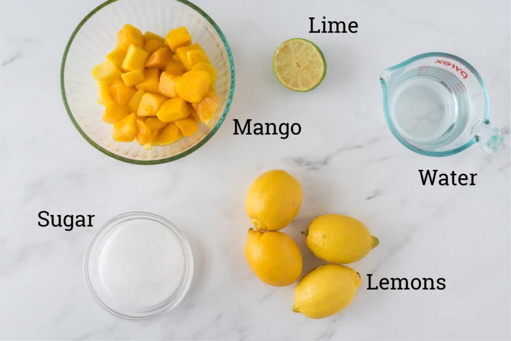 ingredients for mango lemonade placed on marble counter with text overlay of names