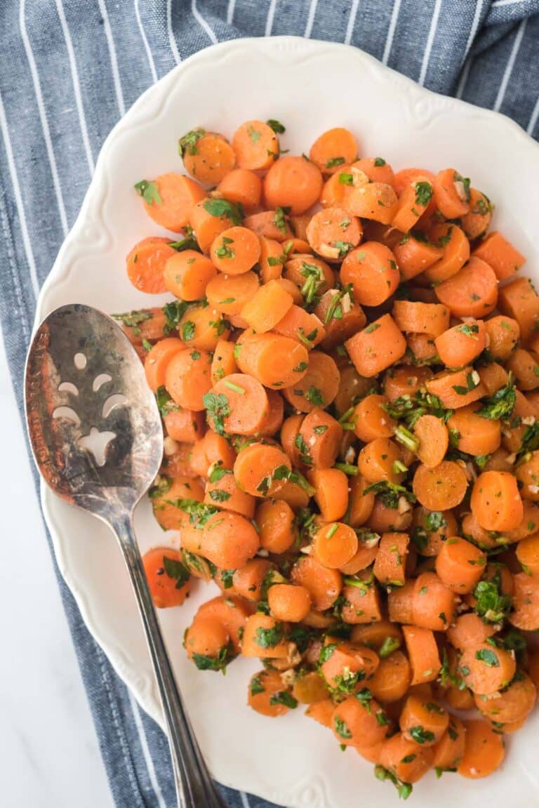 overhead view of moroccan carrot salad on white platter with serving spoon