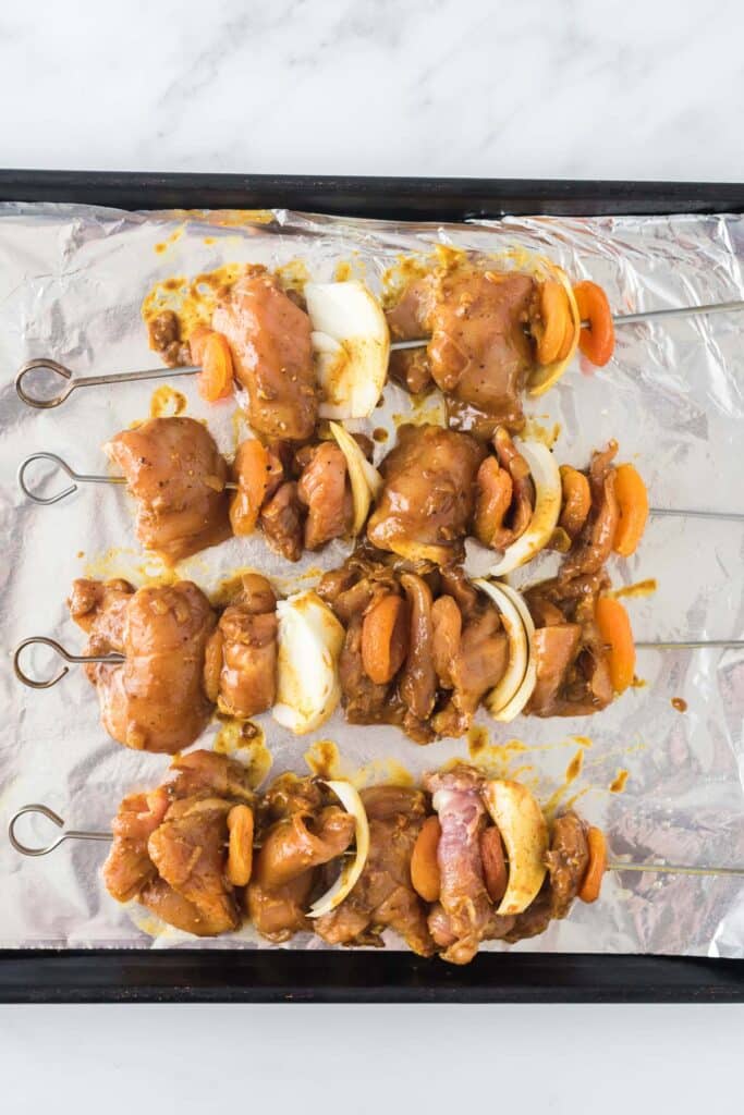 chicken skewers with onion slices and apricots covered in marinade