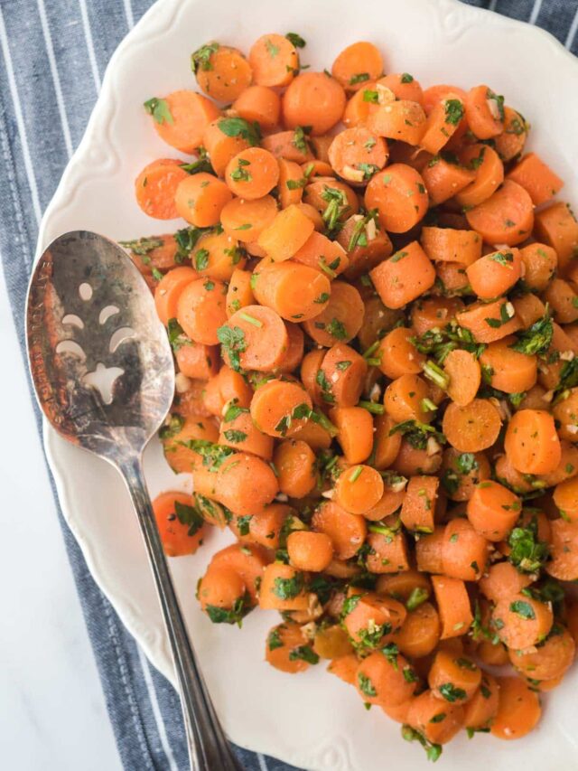 overhead view of moroccan carrot salad on white platter with serving spoon