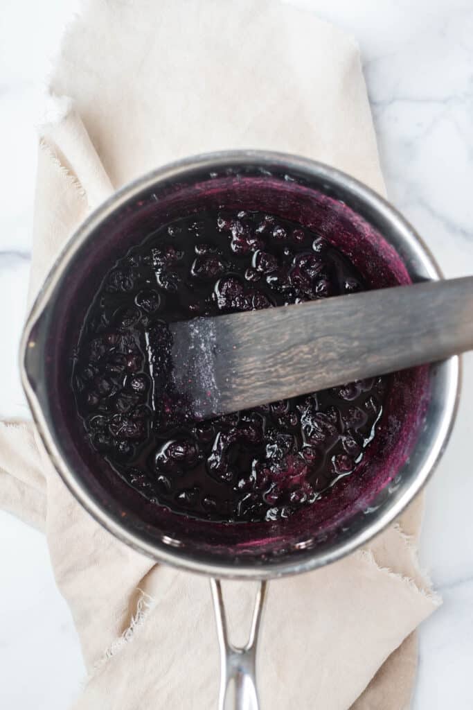 cooked blueberry syrup in saucepan with wooden spatula