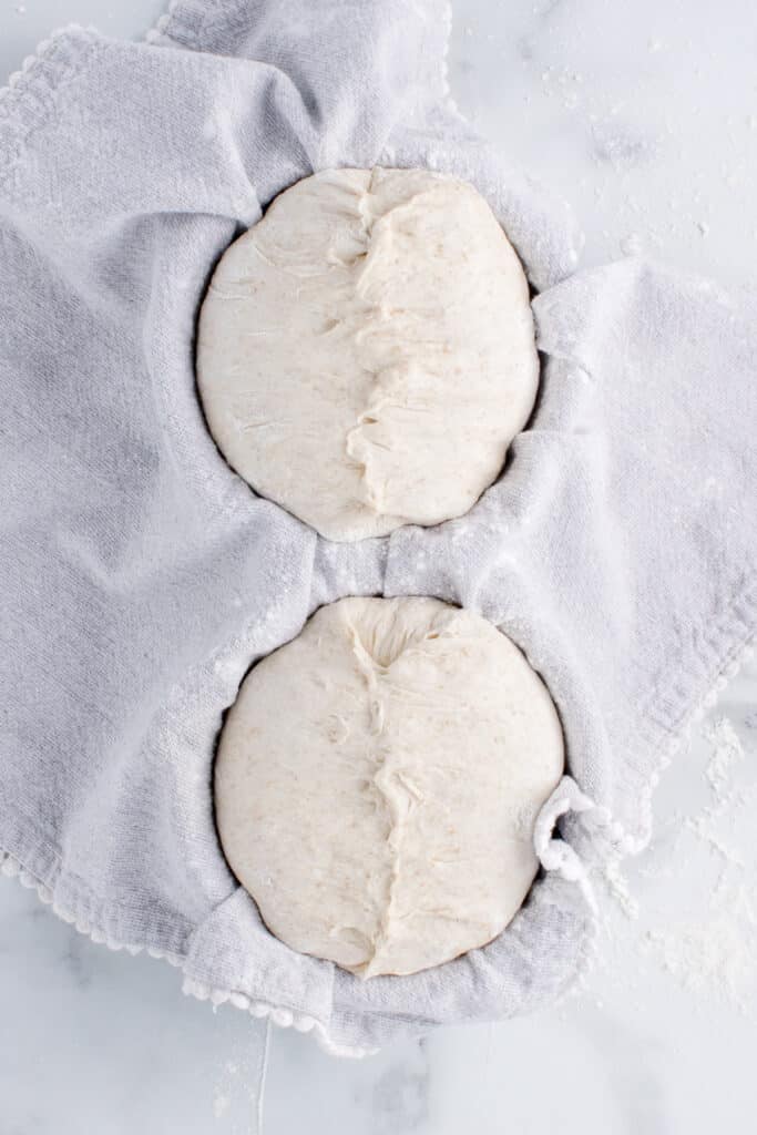 two balls of dough in kitchen towel ready for proofing