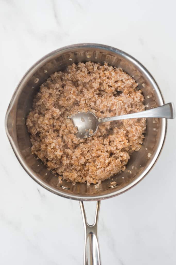 cooked bulgur in small saucepan with spoon