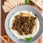 whipped feta dip topped with honey and pistachios and figs with slices of pita to dip on wooden cutting board