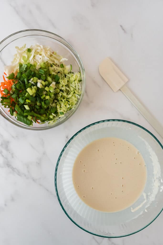 two large mixing bowls - one with shredded vegetables and one with mixed batter