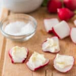 wooden cutting board with sliced radishes with butter and salt