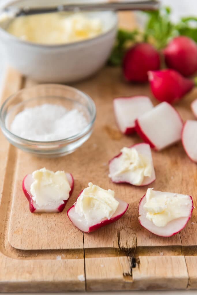 wooden cutting board with sliced radishes with butter and salt 