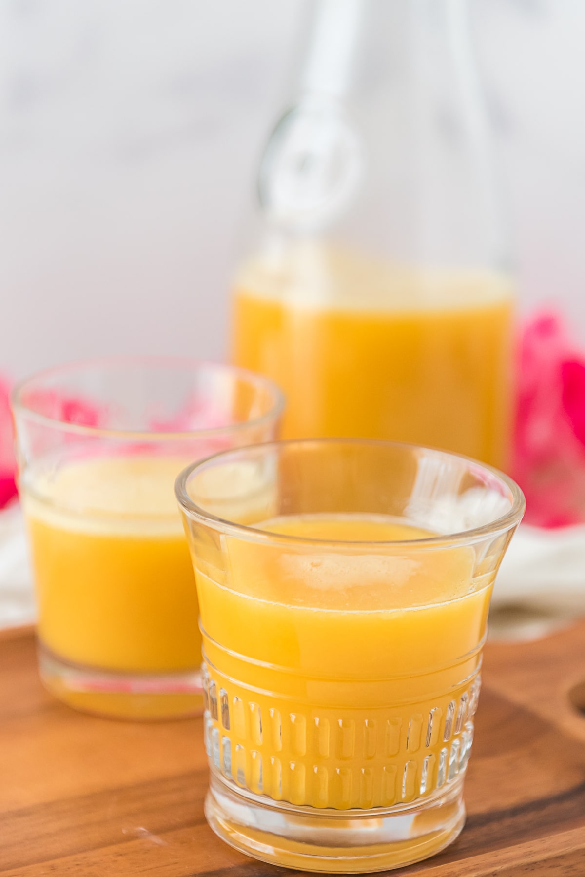 two small glasses filled with pot juice in front of pitcher