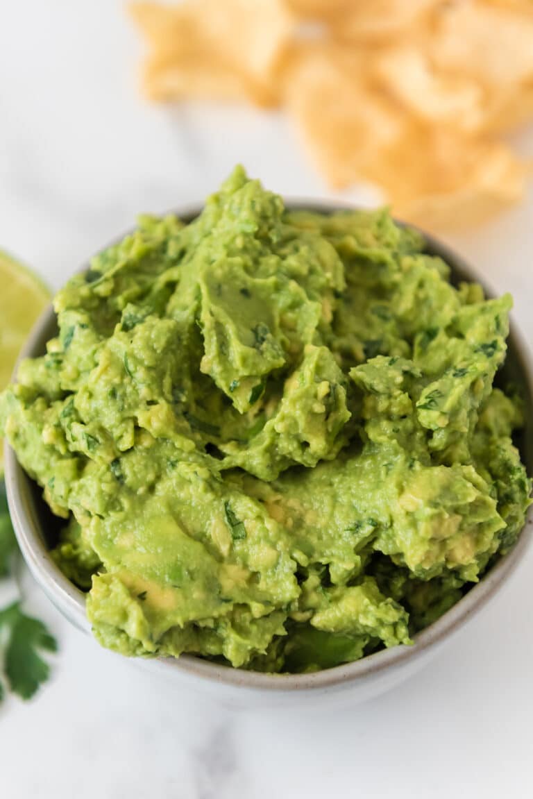 homemade guacamole in small grey bowl with chips blurred in background