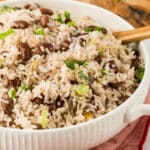 white dish with Jamaican rice and beans with green onion garnish
