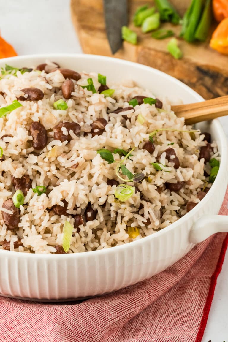 white dish with Jamaican rice and beans with green onion garnish