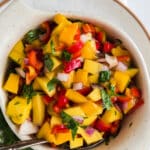 closeup of bowl with fresh mango salsa and spoon