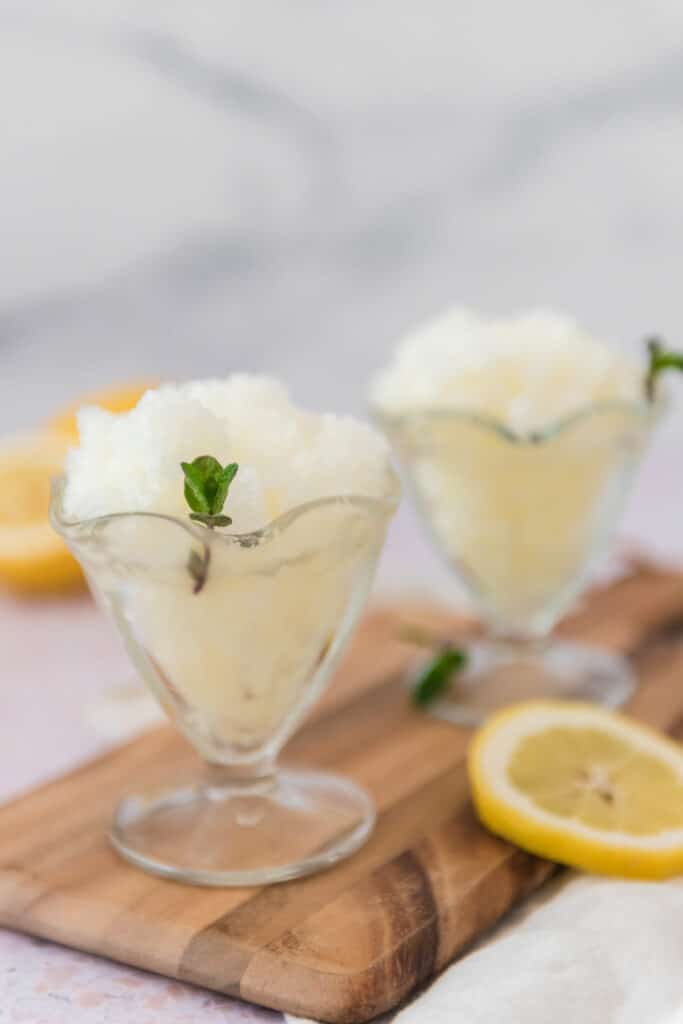 Italian lemon granita in glass ice cream bowls with mint surrounded by lemon slices