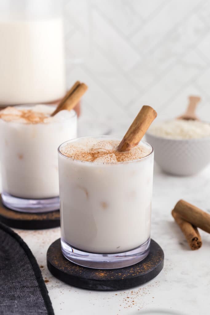 two glasses of horchata with cinnamon sticks as garnish 