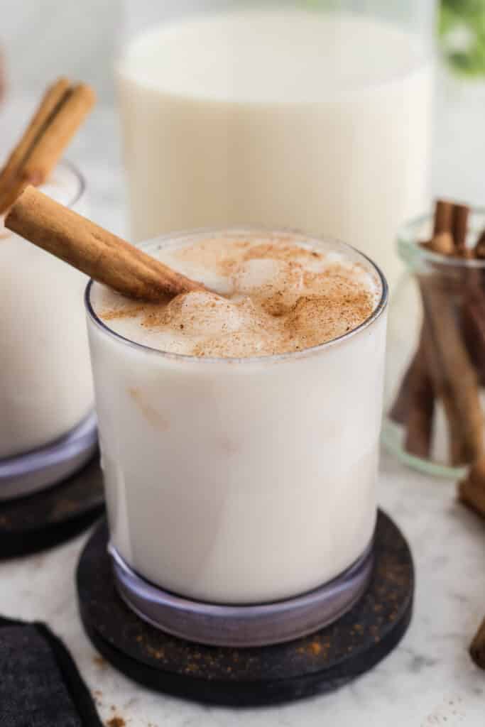 glass of horchata with cinnamon stick with ingredients in background