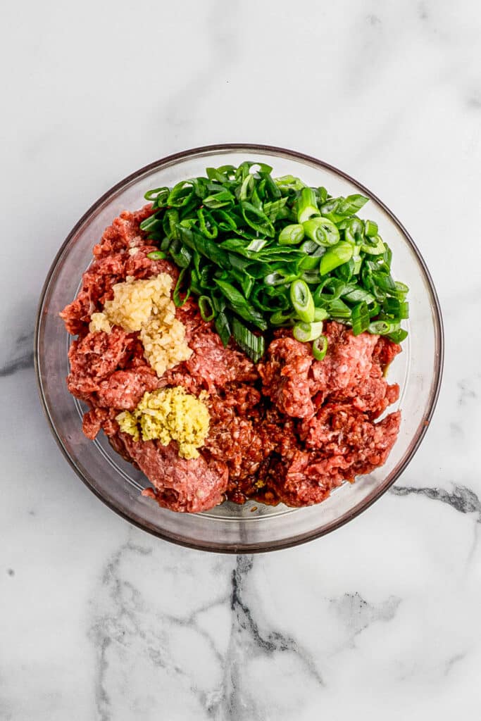 glass mixing bowl with ingredients for ginger beef dumplings
