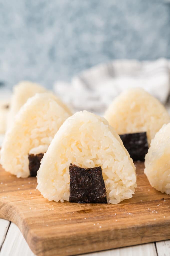 closeup of onigiri on wooden cutting board standing up on end