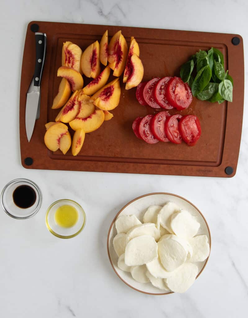 peach caprese prep - slicing tomatoes and peaches and mozzarella